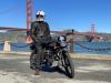 A man on a motorcycle in front of the golden gate bridge.